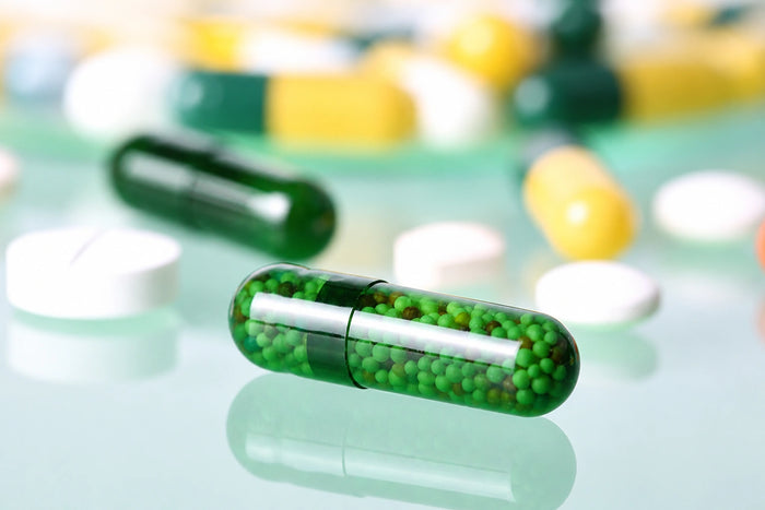 Still-Life-Aufnahme einer transparenten grünen Kapsel mit Mikropellets in Makroansicht. Modernes Pharma- und Labormotiv für Hautpflege, Kosmetik, Wirkstoffe und wissenschaftliche Produktentwicklung.