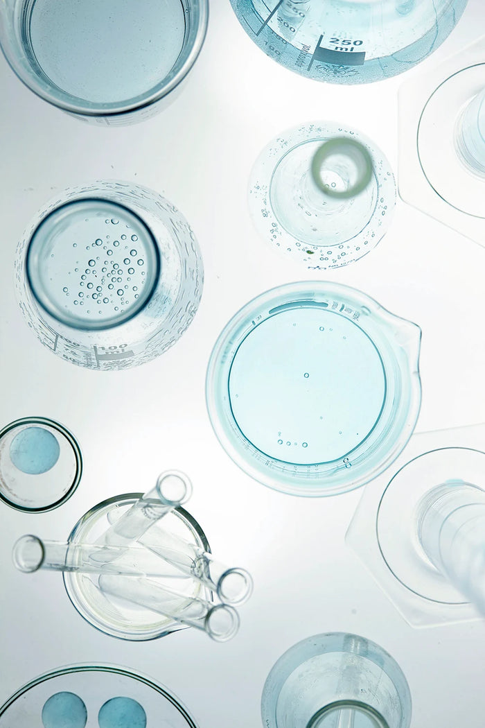 Still-Life-Laborfoto mit transparenten Bechergläsern, Kolben und Laborgefäßen. Modernes Labor-Setting für Hautpflege, Kosmetik und Pharma.